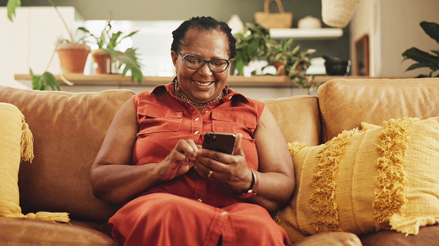 older woman on couch smiling at cellphone