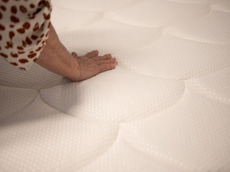 Woman touching the surface of the DreamCloud Premier Memory Foam mattress