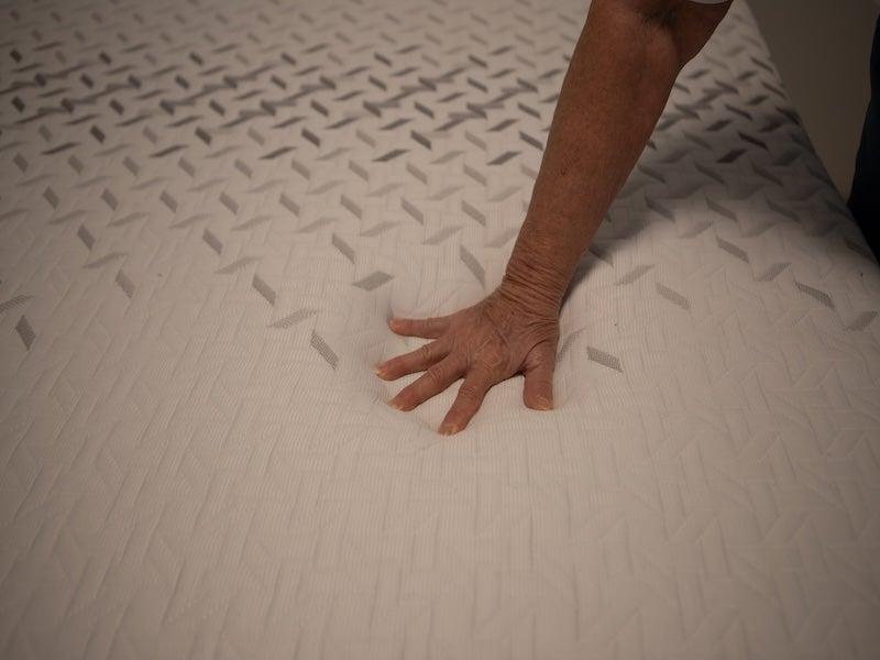 A hand pressing into the top of the Nectar Premier Memory Foam mattress