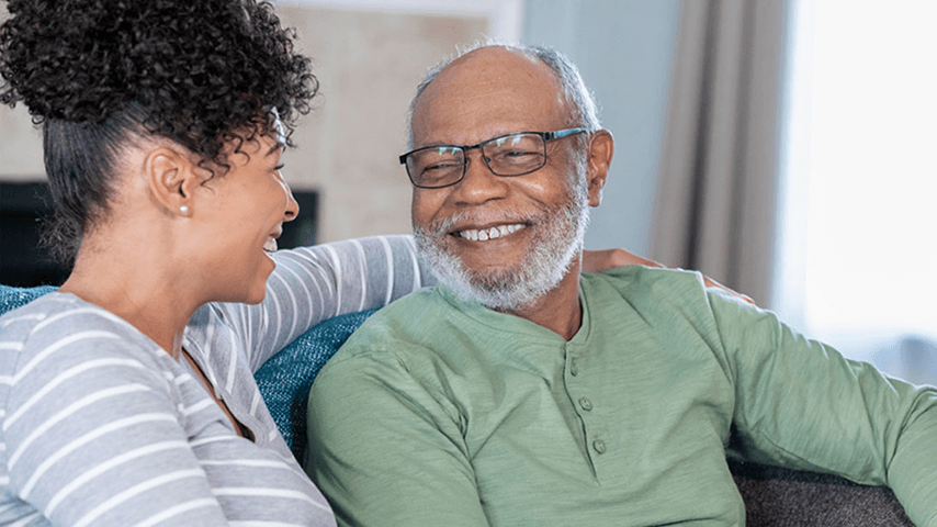 Smiling adult daughter and older father on couch
