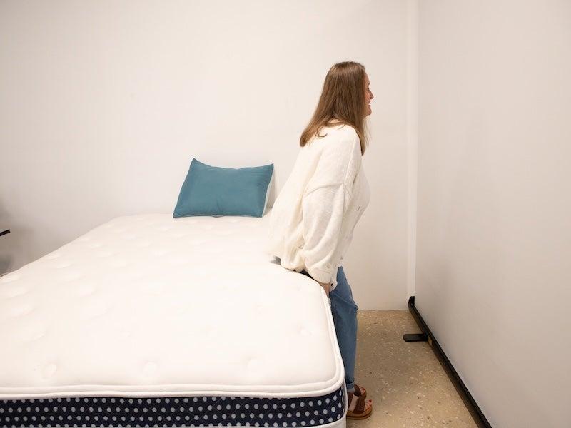 A woman sits down on the WinkBed Plus