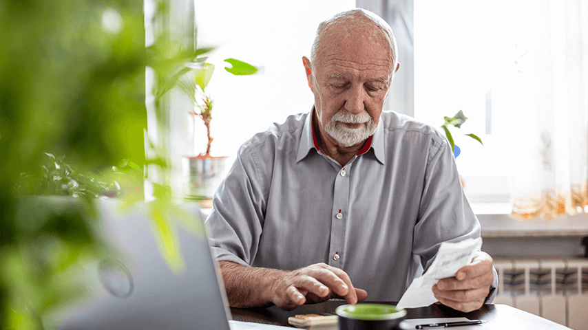 man holding paper receipts and working on calculator