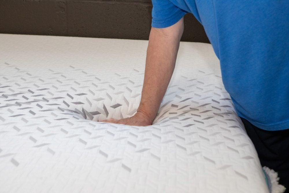 A man’s hand presses into the Nectar Premier Hybrid mattress