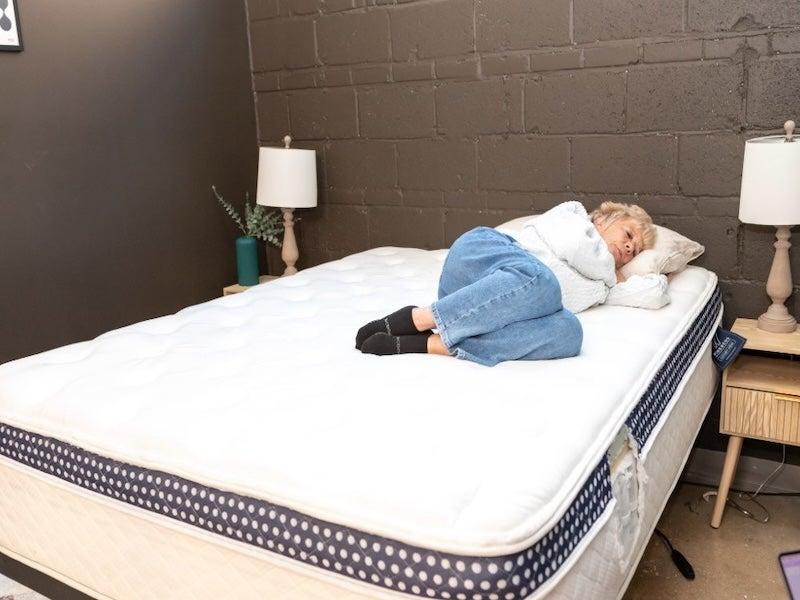 A woman lies on her side on the WinkBed Luxury firm hybrid mattress.