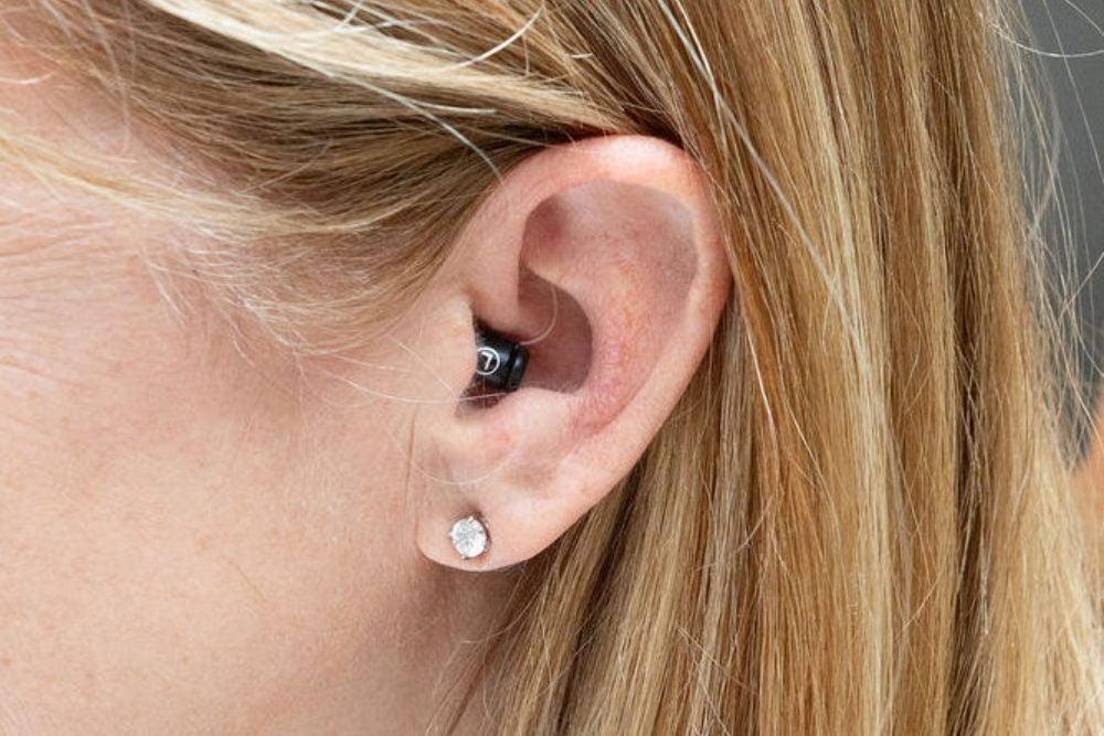 Small black hearing aid in woman's left ear