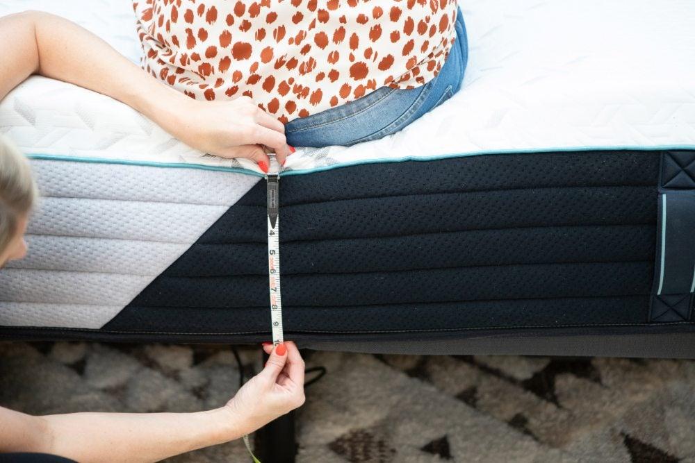 Woman measures how far the edges of the Nectar Premier Memory Foam sink under weight