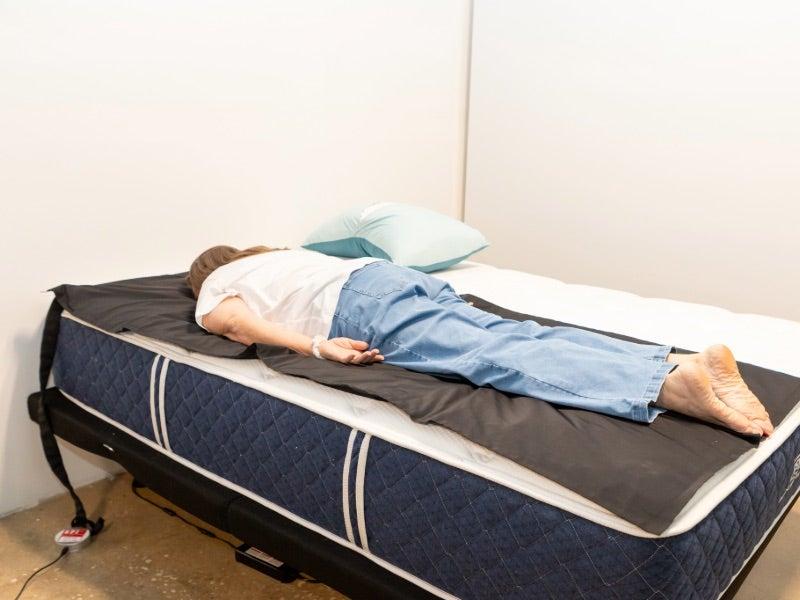A woman lying face down on a pressure map device on the Signature Hybrid mattress