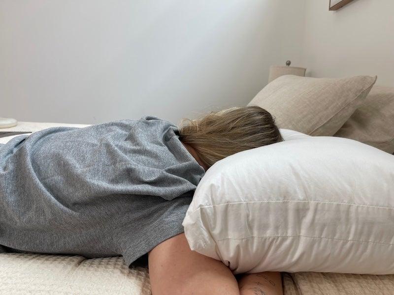 A female tester in a grey shirt evaluates the Silk & Snow for side sleeping