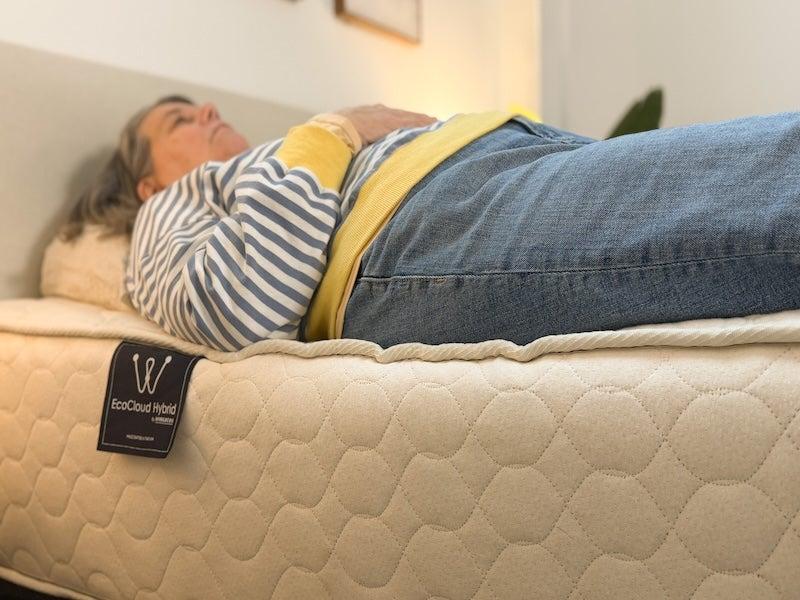 A woman lies on her back near the edge of the WinkBed EcoCloud mattress.