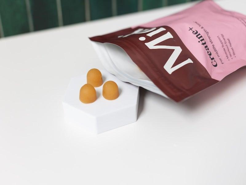 Orange gumdrops spill out of a pink Midi baggie on its side