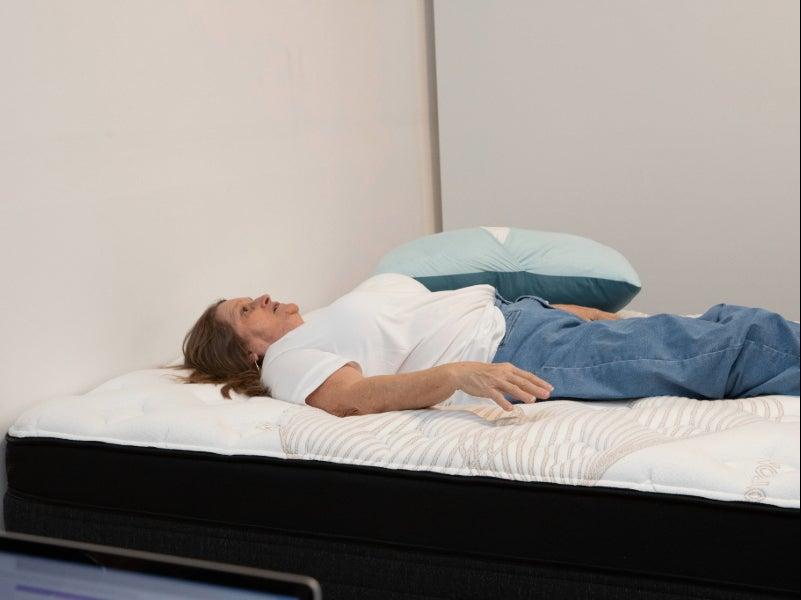 A woman lies on her back on the Nolah Evolution Luxury Firm mattress