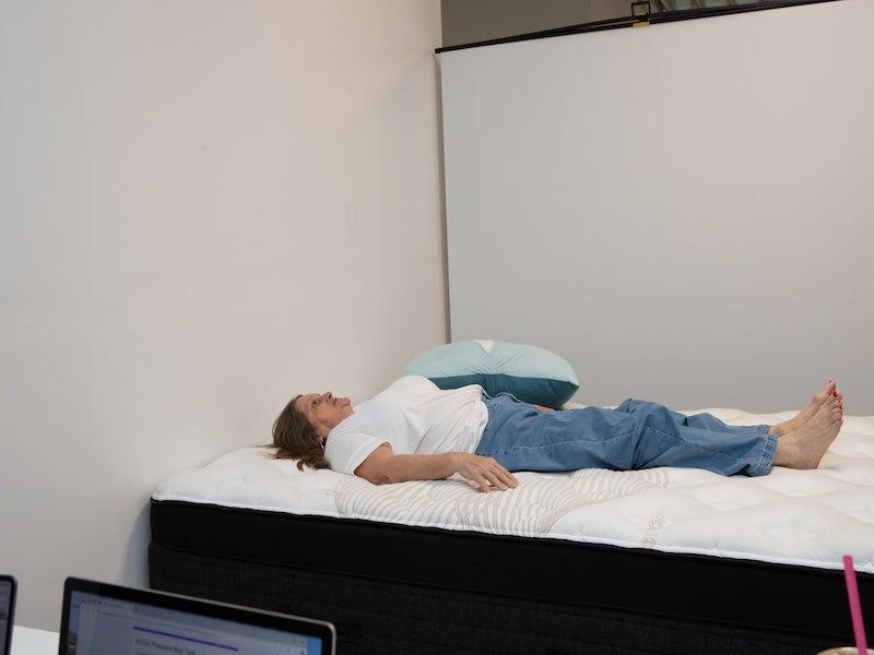A woman in a white shirt lies on her back on the Nolah Evolution Luxury Firm