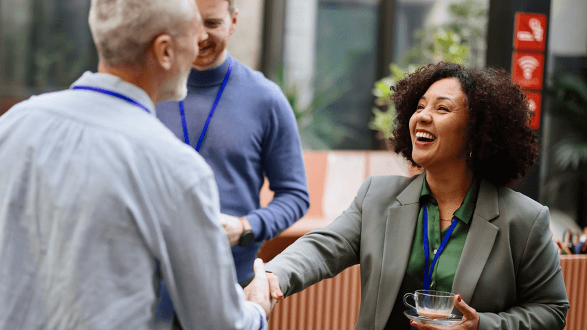 A woman shakes hands with a man at a professional event
