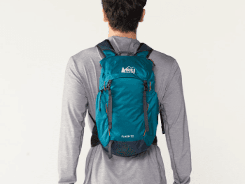 Model in long-sleeved gray shirt wearing a teal-colored REI Co-op backpack