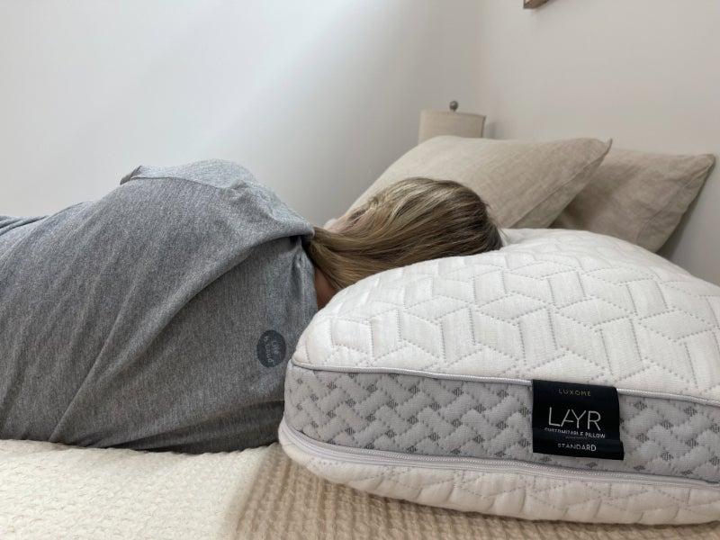 The back of a person sleeping on their side with their head resting on the Luxome LAYR pillow