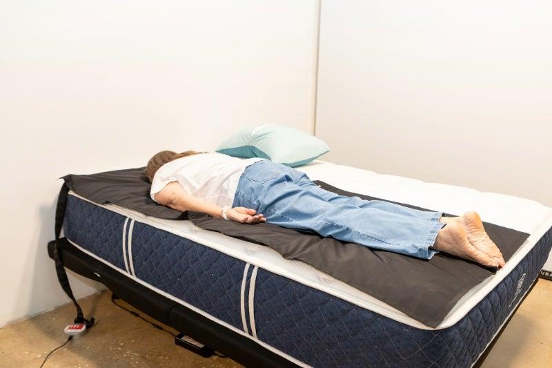 A woman lying on her stomach on the Brooklyn Bedding Signature Hybrid mattress to test its pressure relief