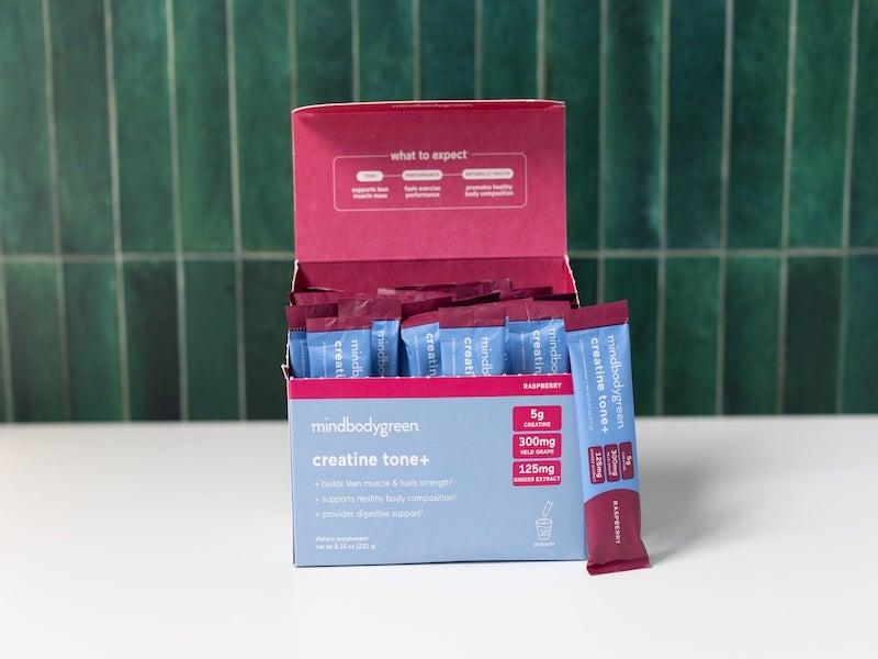 Blue and magenta box of Mindbodygreen Creatine Tone+ packets with one packet propped up outside the box