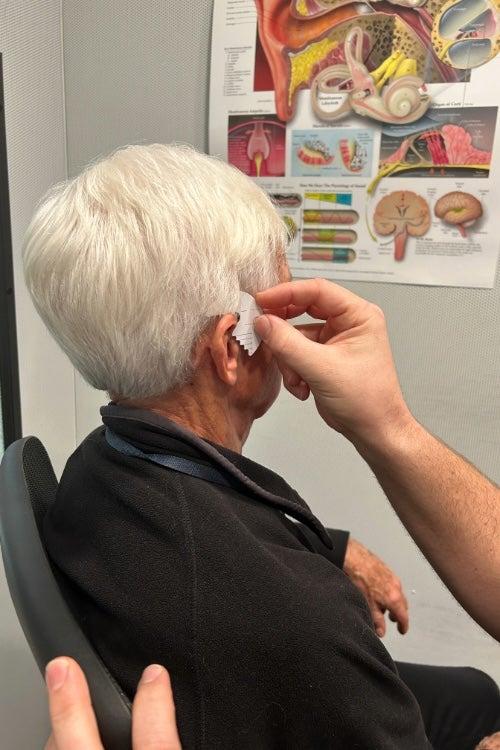 A man sitting in a chair while being fitted for hearing aids at Costco