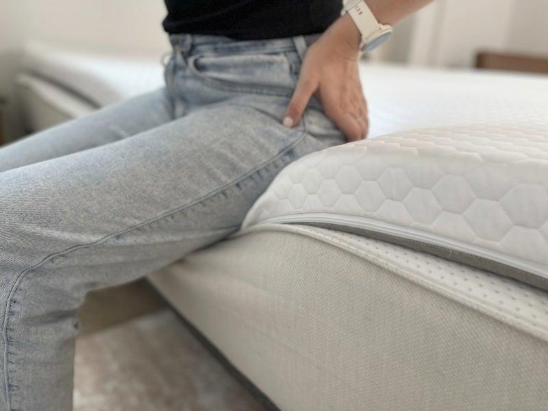 A woman sits on the edge of the Bear Pro topper