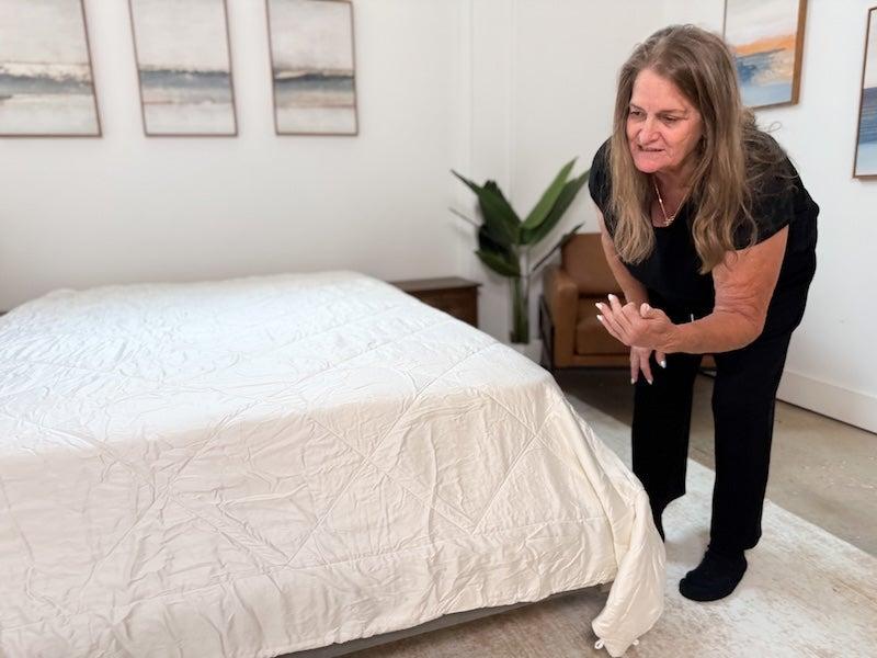 A tester bends down next to a bed to look at the Cozy Earth comforter.