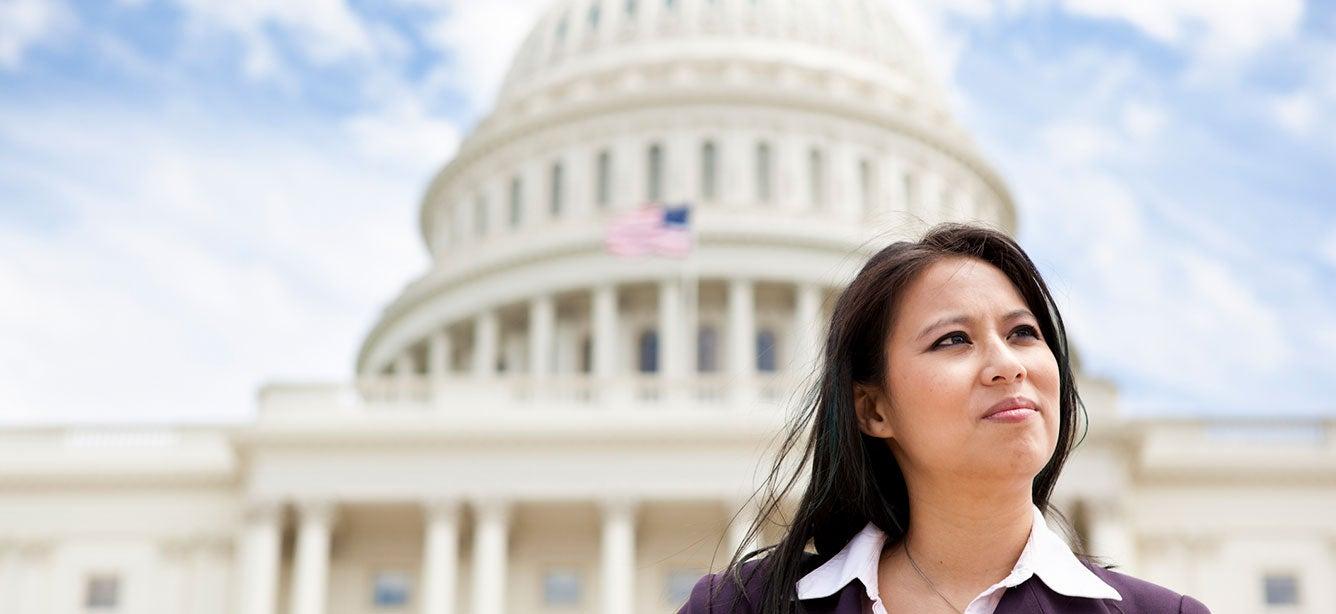 Asian woman looking thoughtful, capitol dome behind her