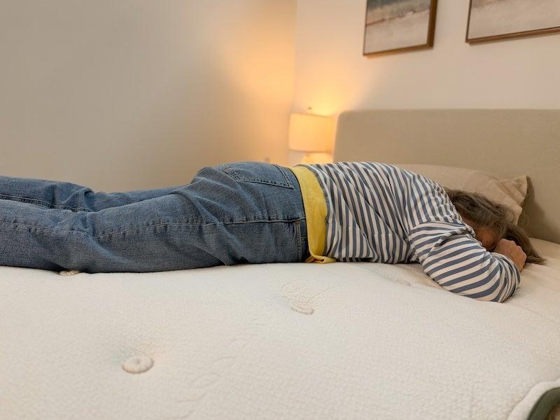 A woman lies facedown on the Avocado Green latex mattress