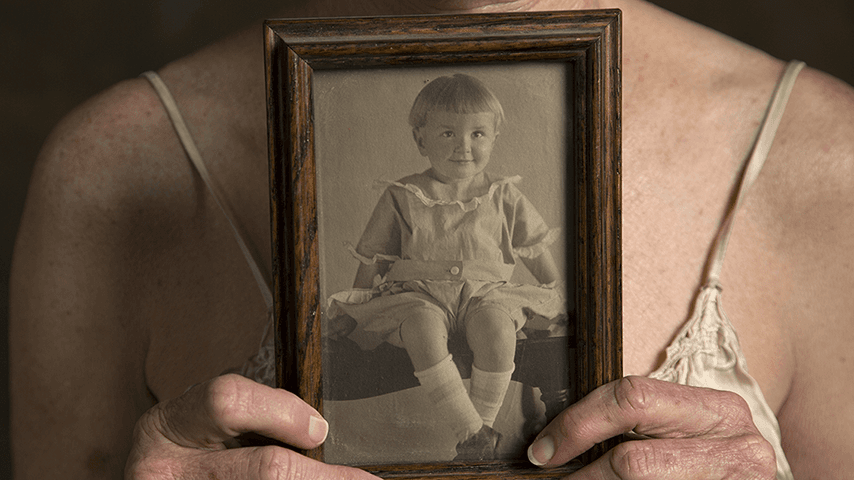 older woman's hands holding photo of her father as a child