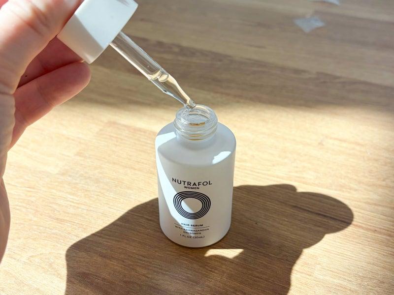 A bottle of Nutrafol hair serum and application dropper