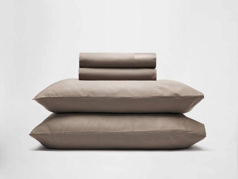 A set of brown Silk & Snow Egyptian Cotton sheets and two pillows against a white background