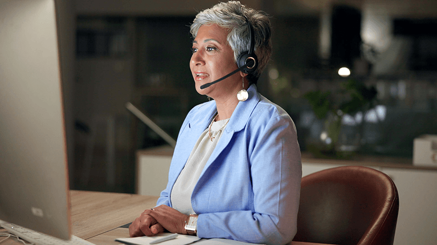 woman at computer wearing headset answering phone call