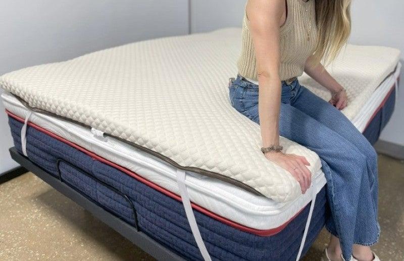 A woman sitting on the edge of the Nolah mattress topper