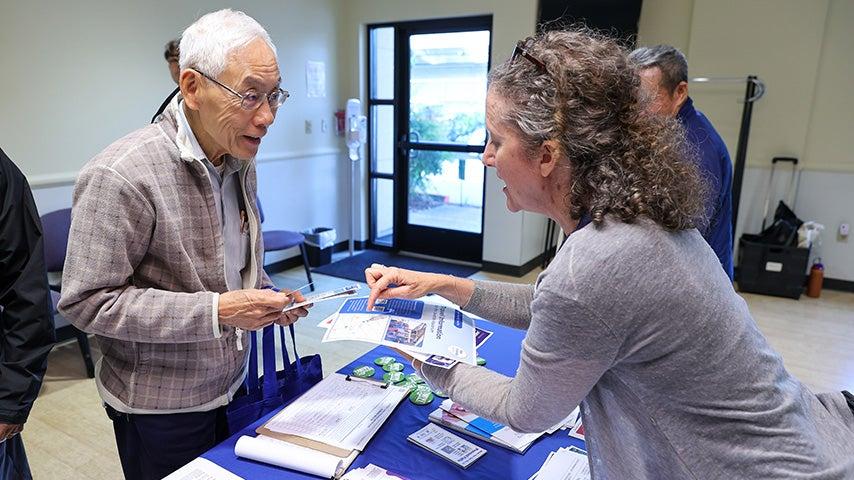 A woman points at a flyer and shows it to a man, who is looking at the flyer.