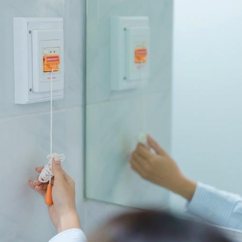 A hand holding and pulling on an emergency button in a bathroom