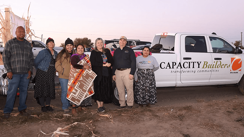 smiling men and women standing in front of Capacity Builders parade float
