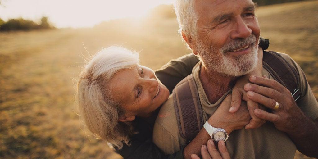 A senior caucasian couple is embracing each other outside as they walk together during sunset.