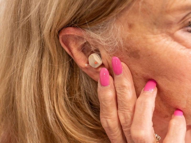 A woman wearing the Linner Saturn earbud-style hearing aid.