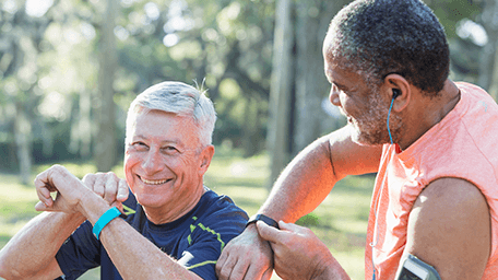two smiling older men touching their fitness trackers