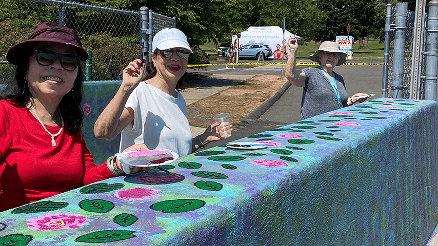 Smiling older women painting on a bridge