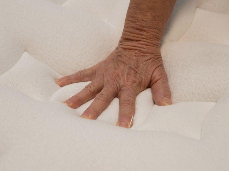 A hand pressing into the plush top of the Nolah Evolution mattress