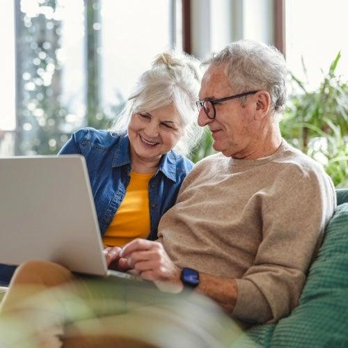 A man and a woman smile while looking at a laptop screen together