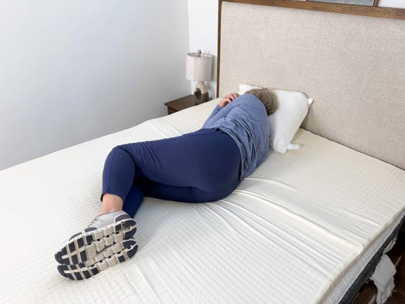 A woman lying on her side on the Silk & Snow Organic Topper