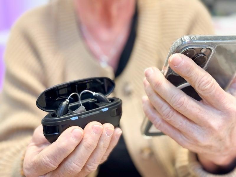 A person holds the Soundbright Discovery in one hand and a cell phone in the other