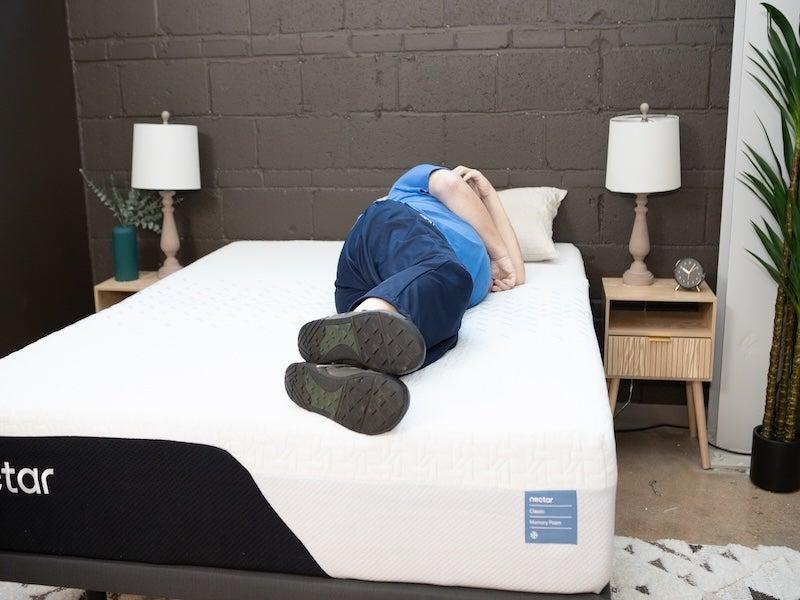 A man in a blue shirt sleeps on his side on the Nectar Classic Memory Foam mattress