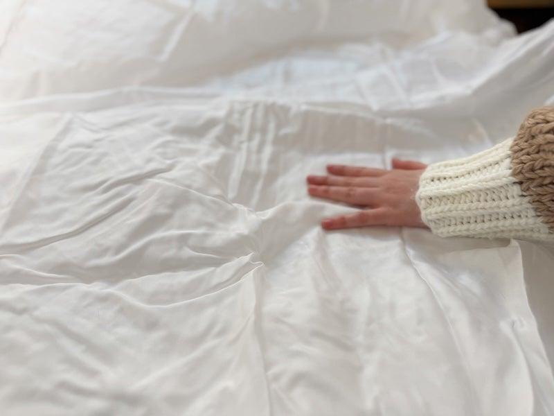 A woman runs her hand over the Bear Tencel Sateen Sheet Set