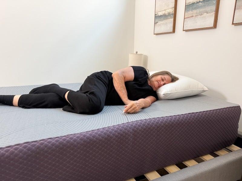 A woman lies on her side on the Purple RestorePlus Hybrid mattress