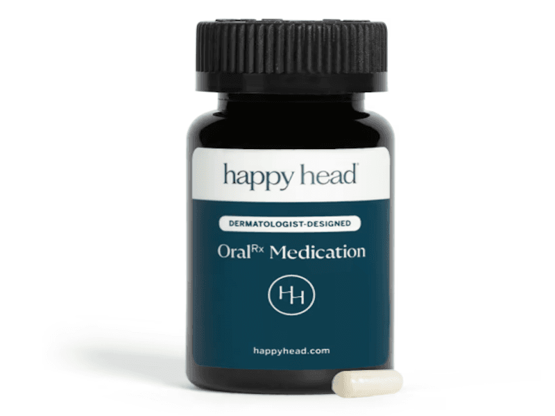 Dark bottle labeled "Happy Head" with "Oral Medication" text, featuring a black cap, and one white capsule beside it.