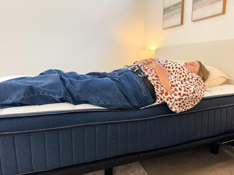 A person shown lying at the edge of a Silk & Snow Hybrid mattress to test edge support