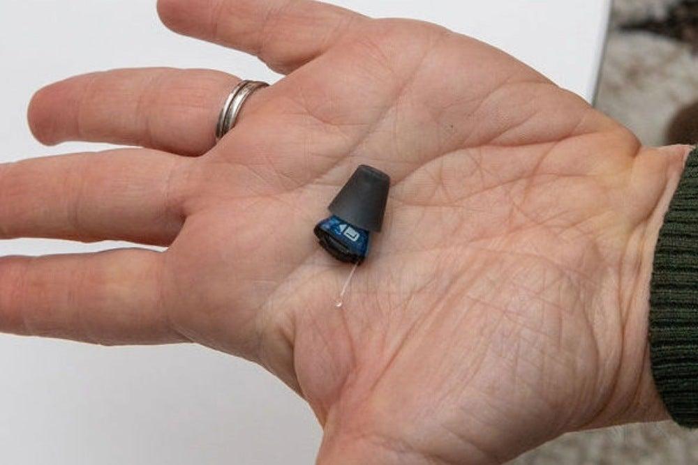 small hearing aid in man's open hand