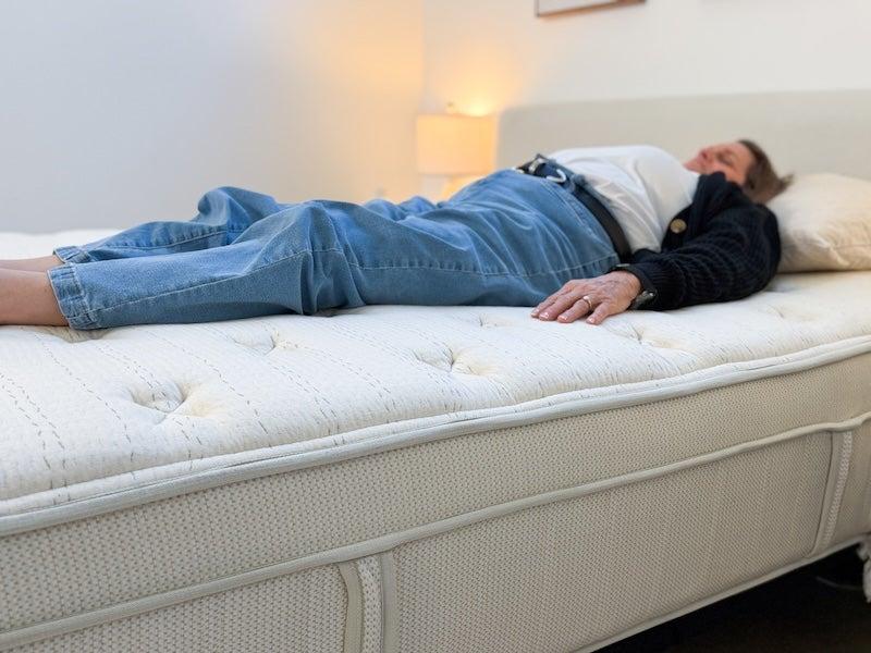 A woman lies on her back on the Leesa Natural mattress
