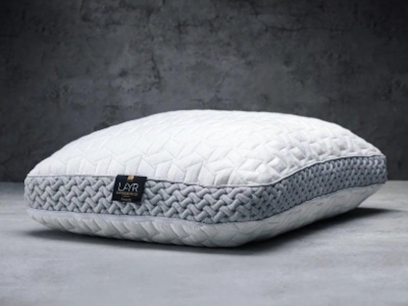 A white Luxome LAYR pillow without a pillowcase in front of a grey carpeted background